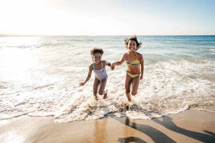 little girls running through the waves on the beach
